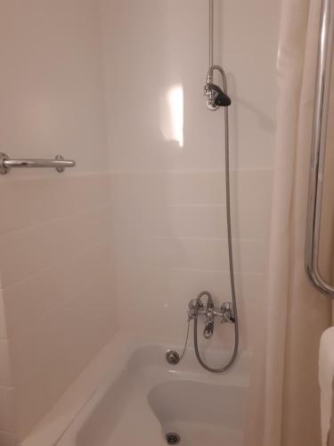 a white bath tub with a shower in a bathroom at Studio Jules De Trooz in Blankenberge