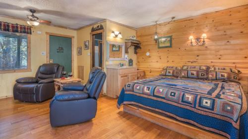 a bedroom with a bed and two chairs at Whispering Pine Cabins in Ruidoso