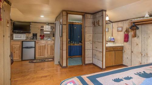 a kitchen with wooden cabinets and a kitchen with a tv at Whispering Pine Cabins in Ruidoso