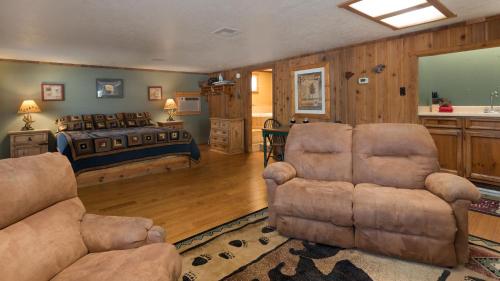 a bedroom with a bed and a couch and chairs at Whispering Pine Cabins in Ruidoso