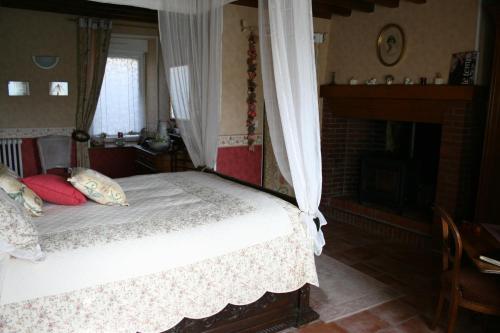 a bedroom with a bed with a canopy and a fireplace at Herbages de Beauvais in Orgères-la-Roche