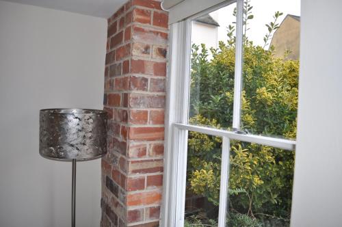 an open window with a brick wall and a lamp at French Horn Cottage in Ware