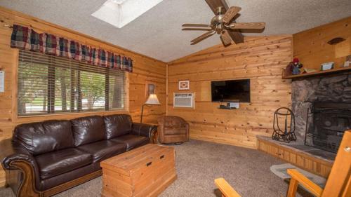 a living room with a leather couch and a fireplace at Whispering Pine Cabins in Ruidoso