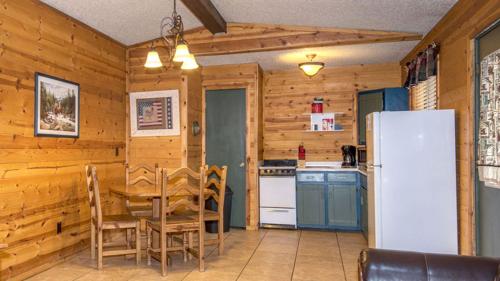 a kitchen with a table and a white refrigerator at Whispering Pine Cabins in Ruidoso