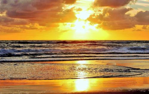 a sunset on a beach with the ocean at Ocean Terrace Suite And Spa Luxury in Nusa Penida