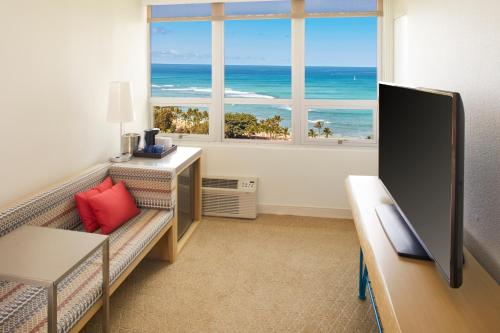 a living room with a couch and a view of the ocean at Queen Kapiolani Hotel in Honolulu