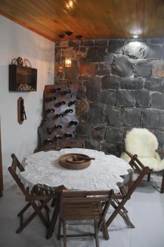 einen Tisch und Stühle in einem Zimmer mit einer Steinmauer in der Unterkunft Aconchego da Serra Edícula in São Joaquim
