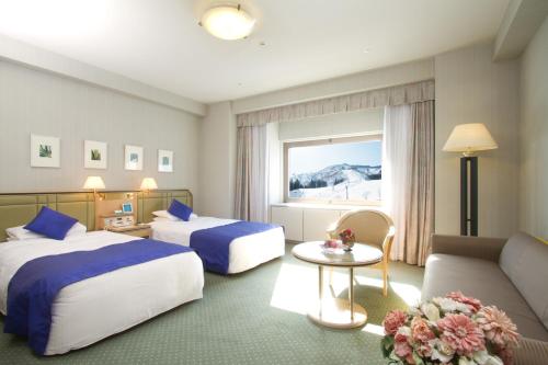 a hotel room with two beds and a couch at NASPA New Otani in Yuzawa