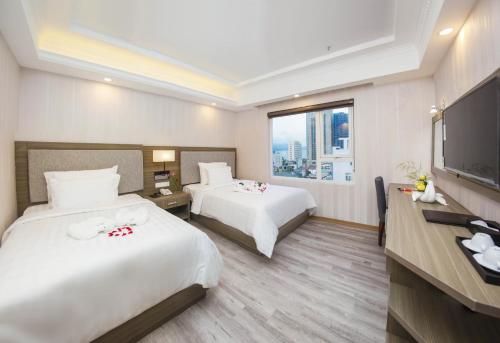 a hotel room with two beds and a flat screen tv at Golden Rose Hotel in Da Nang