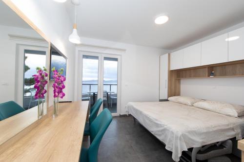 een slaapkamer met een bed en een tafel met paarse bloemen bij Apartment Valentina in Brela