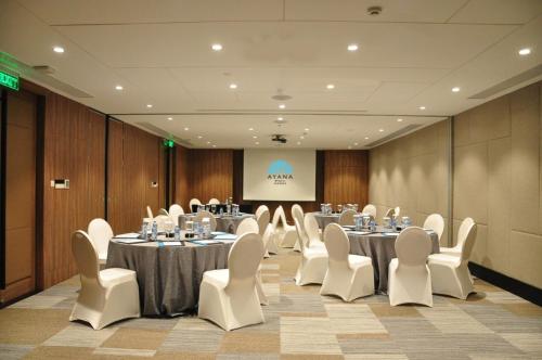 a conference room with tables and white chairs and a screen at AYANA Midplaza JAKARTA in Jakarta