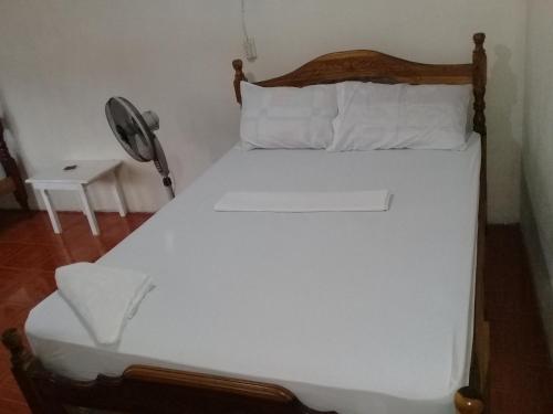 a white bed in a room with a fan at Guest House Nena in Moyogalpa