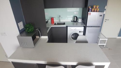 a kitchen with a washing machine and a refrigerator at D'Kroll Tamarind Cyberjaya 1 Bedroom Premium Suite with Netflix in Cyberjaya