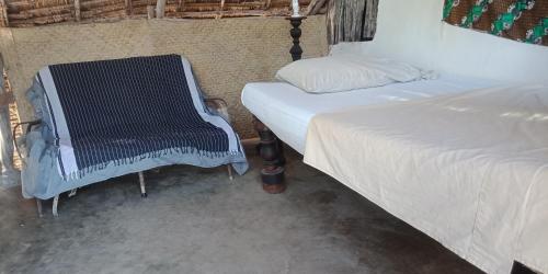 a bedroom with two beds and a chair in it at Wildebeeste Lamu in Lamu