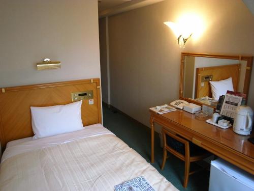 a bedroom with a bed and a desk with a mirror at Hotel Kizankan in Tokyo