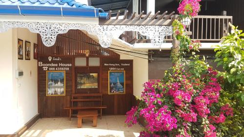 a building with a bench and flowers in front of it at Boondee House in Mae Hong Son