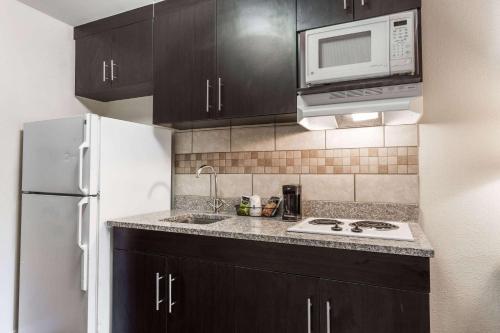 a kitchen with black cabinets and a white refrigerator at Days Inn & Suites by Wyndham Rocky Mount Golden East in Rocky Mount