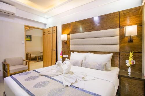 a bedroom with a large white bed with a wooden headboard at White Palace Hotel in Dhaka