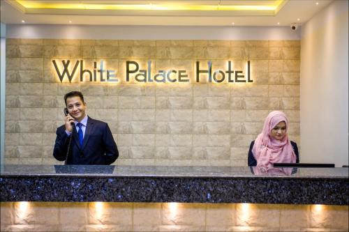 a man talking on a cell phone in front of a white palace hotel at White Palace Hotel in Dhaka