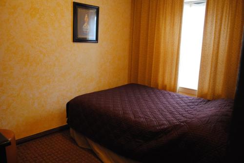 a small bed in a room with a window at Chinatown Hotel Chicago in Chicago