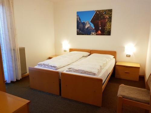 a bedroom with two beds and a painting on the wall at Residence La Zondra in Pozza di Fassa
