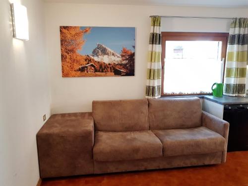a brown couch in a living room with a window at Residence La Zondra in Pozza di Fassa