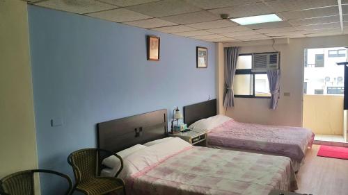 a bedroom with two beds and a table and chairs at Fu Da Guest House in Hualien City