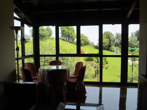 a room with a table and chairs and a large window at Hotel Finca La Mansión in Llanes