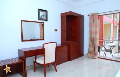 a room with a desk with a chair and a mirror at RJ Mahaal Hotel in Kilinochchi