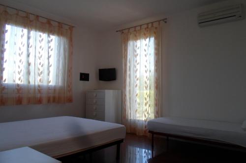 een slaapkamer met 2 bedden en 2 ramen bij DIMORA Simona in Caorle