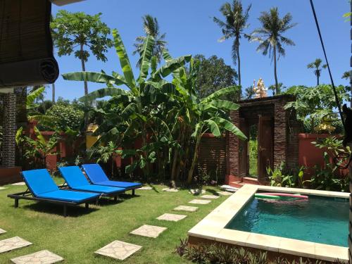 a yard with blue chairs and a swimming pool at Bali Blue Gecko Villas in Amed