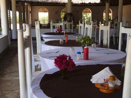 a group of tables with white chairs and flowers on them at Karibuni Hotel & Villas in Mambrui