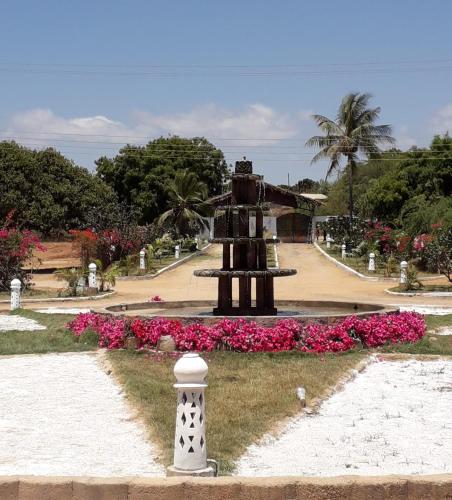 a fountain in a park with pink flowers at Karibuni Hotel & Villas in Mambrui