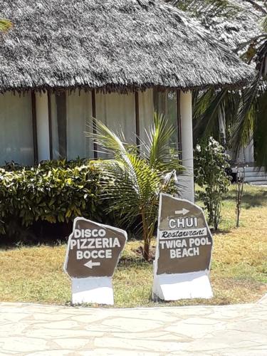 two signs in front of a building with a resort at Karibuni Hotel & Villas in Mambrui
