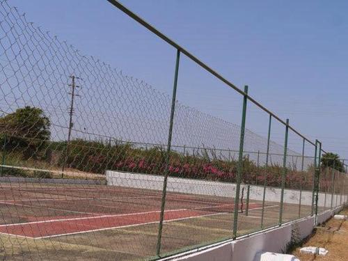 a fence on a tennis court with pink flowers at Karibuni Hotel & Villas in Mambrui