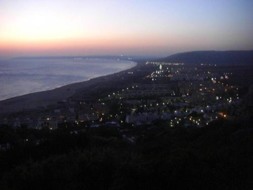 a view of a city with the ocean at night at ATICO DUPLEX APARTAMENTO ATLANTERRA PLAYA, ZAHARA DE LOS ATUNES in Zahara de los Atunes