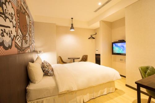 a hotel room with a bed and a table and a television at Just Live Inn-Taipei Station in Taipei