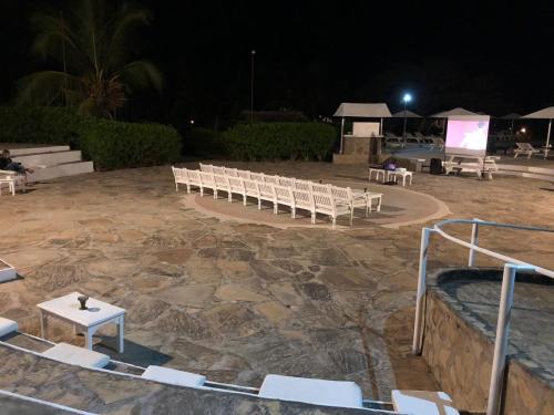 a group of white chairs and a stage at night at Karibuni Hotel & Villas in Mambrui