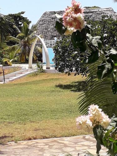 a view of a park with a arch and flowers at Karibuni Hotel & Villas in Mambrui