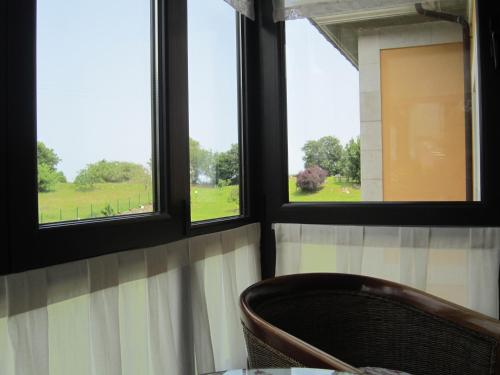 a chair sitting in a room with three windows at Hotel Finca La Mansión in Llanes