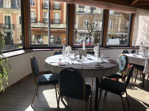 a dining room with tables and chairs and windows at Hôtel de Paris in Châtel-Guyon