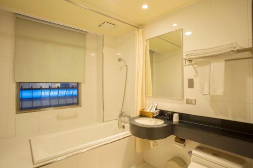 a bathroom with a sink and a tub and a mirror at Just Live Inn-Taipei Station in Taipei