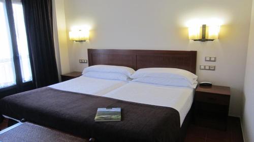 a bed in a hotel room with a book on it at Hotel Finca La Mansión in Llanes