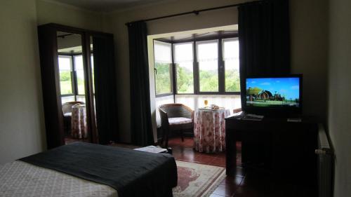 a bedroom with a bed and a tv and a window at Hotel Finca La Mansión in Llanes