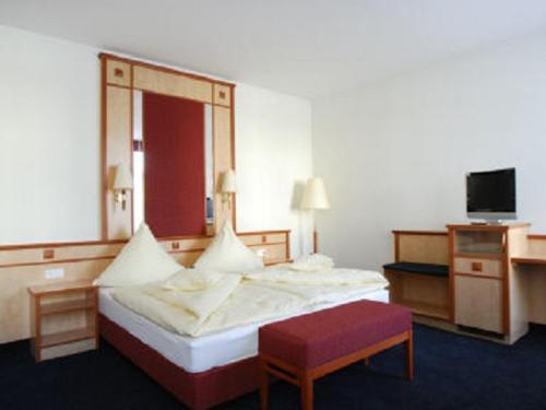 a hotel room with a bed and a bench and a tv at Alte Reichsbank in Schweinfurt