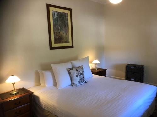 a bedroom with a white bed with two night stands and two lamps at Barossa Shiraz Estate in Lyndoch
