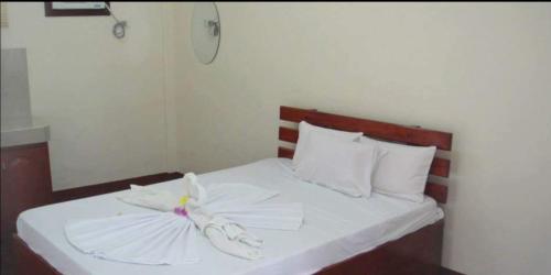 een slaapkamer met een bed met witte lakens en kussens bij AJ Travellers Inn - Annex in Boracay