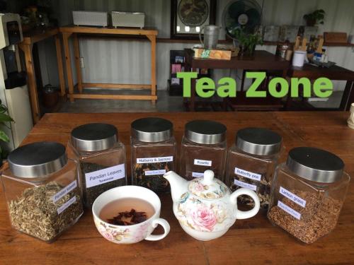 a table with jars of teazos and a cup of coffee at Baan Boom Boxes Eco Friendly Resort in Mae Nam