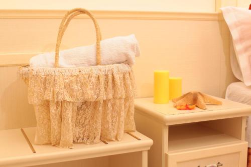 a basket on a table with a candle and a bed at Hotel Stefan Room & Breakfast in Gatteo a Mare