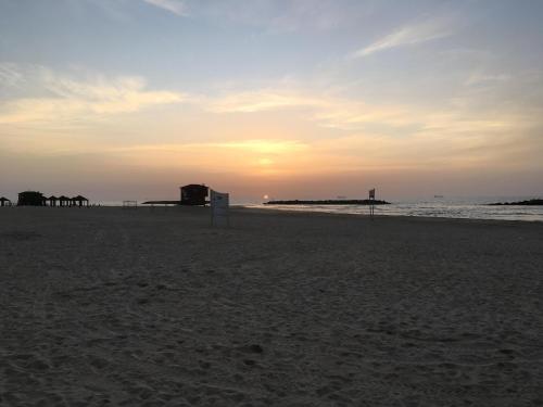 a sunset on a beach with a sign in the sand at Marina Breeze in Ashqelon